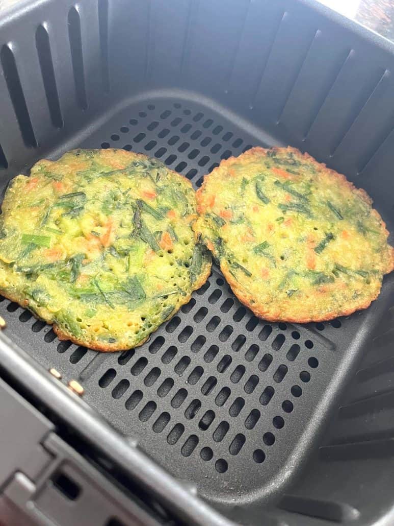 Two crispy Trader Joe’s scallion pancakes cooked in the air fryer basket, showing their golden brown and perfectly cooked texture.