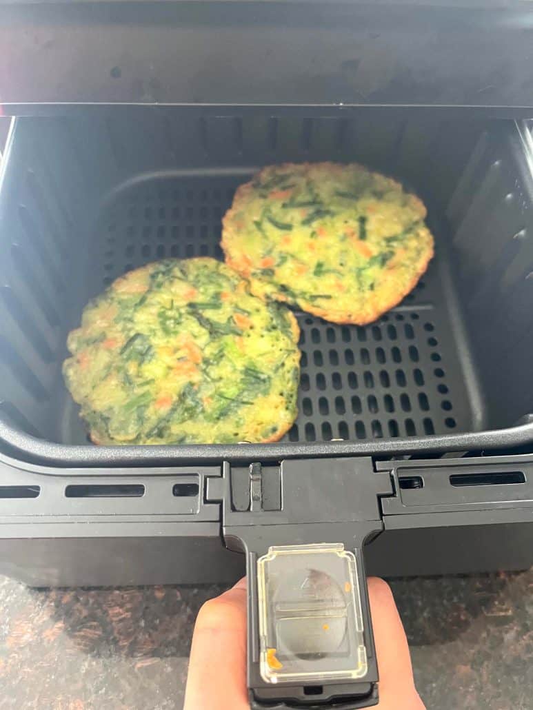 Two frozen Trader Joe’s scallion pancakes placed inside an air fryer basket, ready to be cooked.