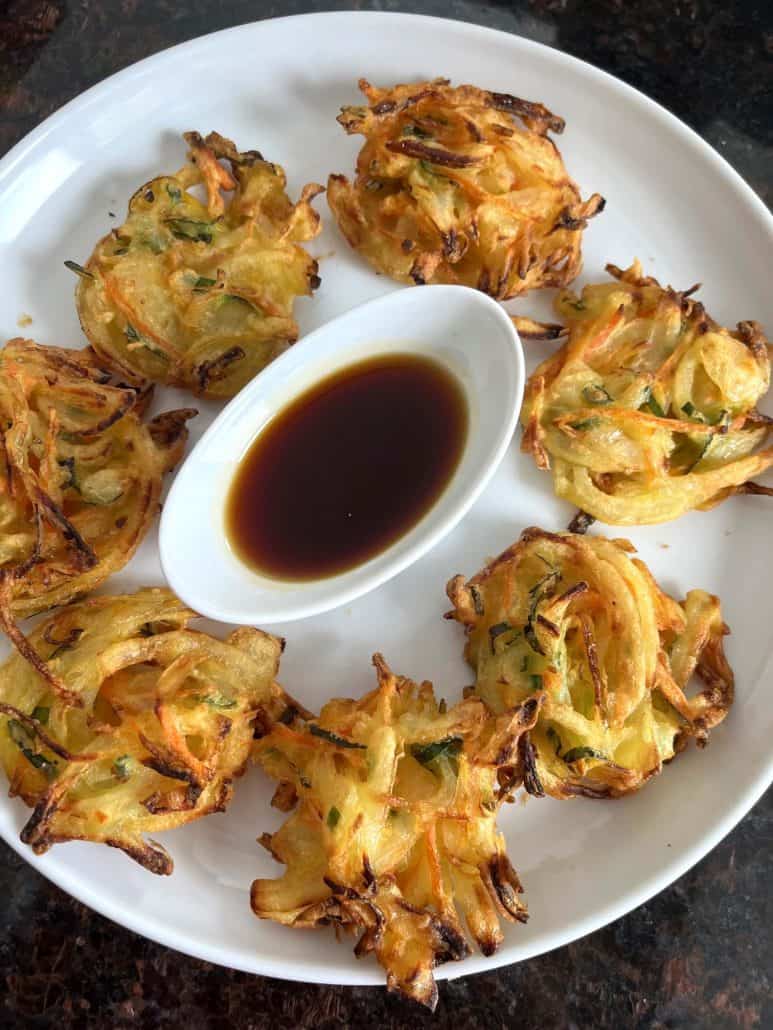 A plate of crispy, golden-brown Trader Joe’s Vegetable Bird’s Nests served with dipping sauce.