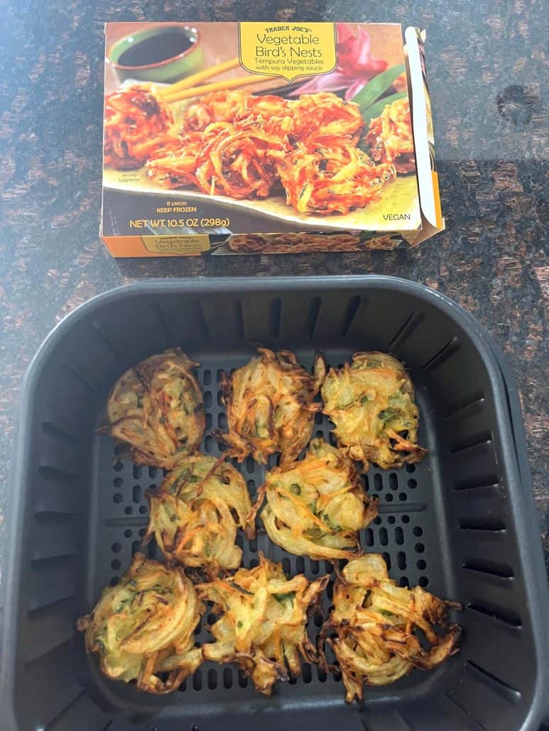 Air-fried Trader Joe’s Vegetable Bird’s Nests in the air fryer basket, golden and crispy, with the original packaging in the background.
