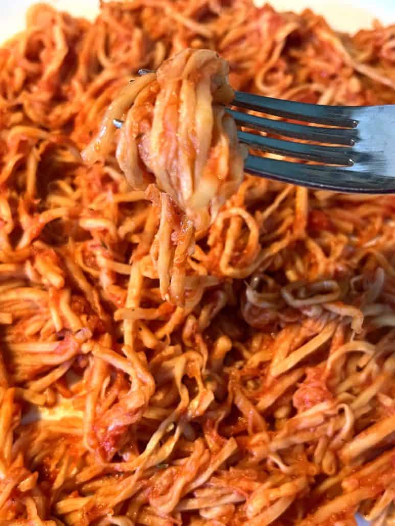 A close-up of a fork twirling the delicious hearts of palm pasta coated in marinara sauce.