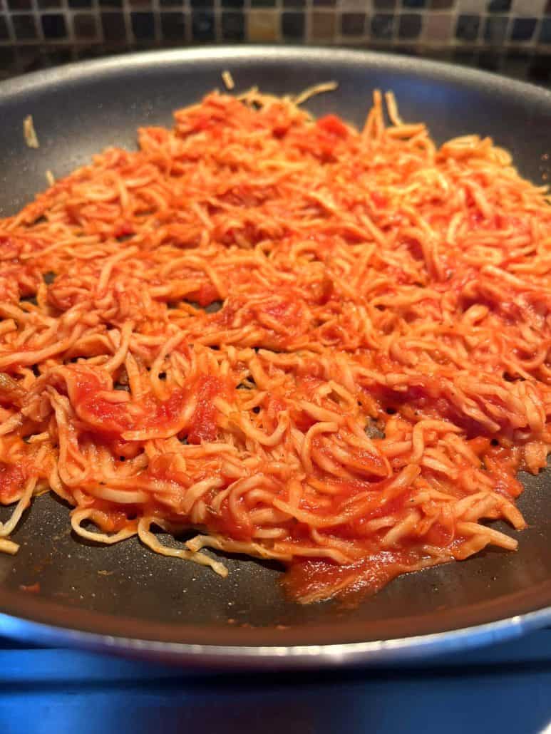Hearts of palm pasta simmering in marinara sauce in a frying pan, showing how easy it is to cook.
