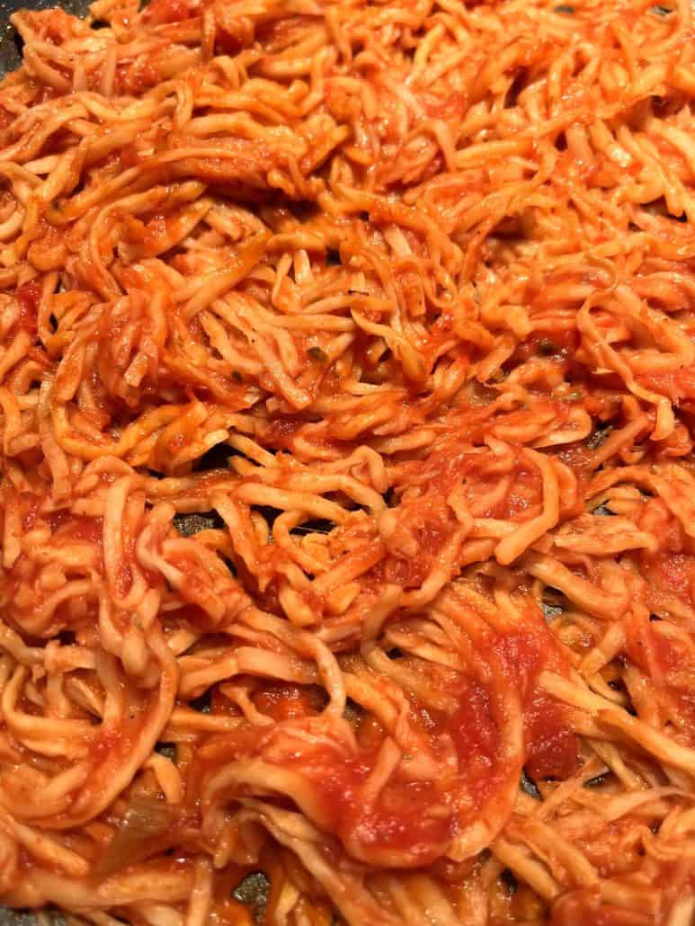 A close-up view of delicious and healthy hearts of palm pasta mixed with marinara sauce.