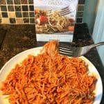 Plate of cooked Trader Joe’s Hearts of Palm Pasta with marinara sauce, served with a fork, with the product packaging in the background. A healthy, low-carb pasta alternative ready to enjoy!