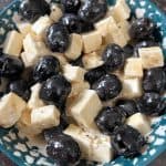 A bowl of marinated olives and feta cheese, coated in Italian dressing—an easy and flavorful appetizer perfect for parties or snacking.