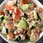 Fresh Mediterranean Tuna Salad in a white bowl with chopped tomatoes, cucumbers, olives, and tuna, dressed with olive oil and lime juice—perfect for a healthy, no-mayo meal.