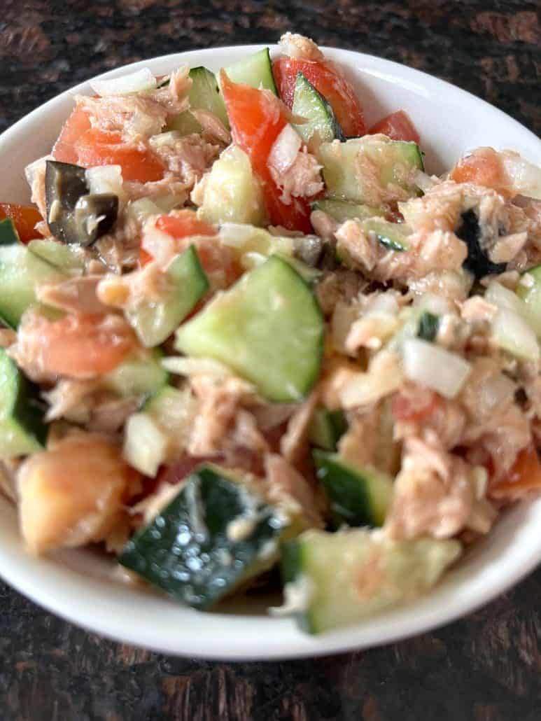 Mediterranean Tuna Salad in a white bowl, packed with fresh ingredients, ready to enjoy.
