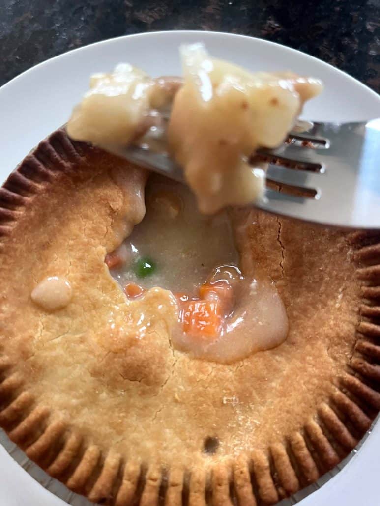 Fork holding a bite of turkey pot pie with creamy filling and vegetables, showing the inside of the air-fried pot pie.