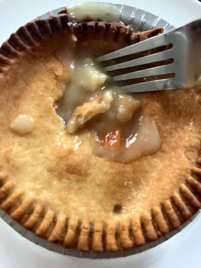 Fork breaking into an air-fried turkey pot pie to reveal hot, creamy filling inside the crispy crust.