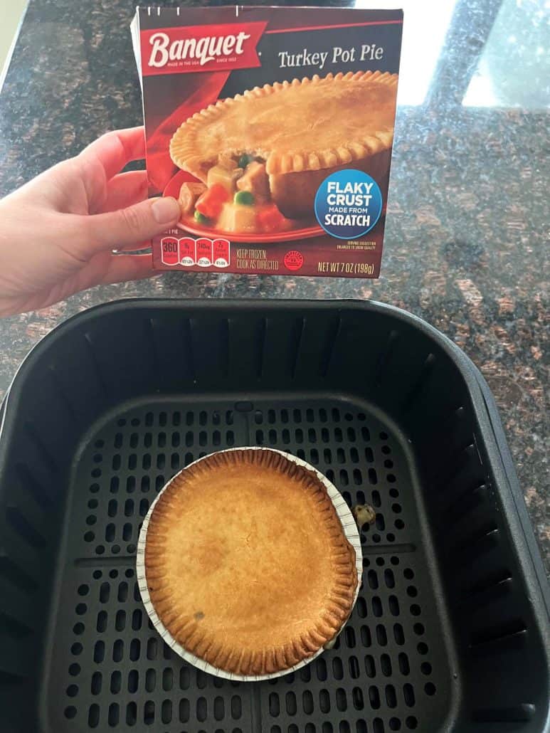 Melanie Mendelson from melaniecooks.com holding a Banquet turkey pot pie box above a cooked pot pie inside an air fryer basket, showing the finished result.