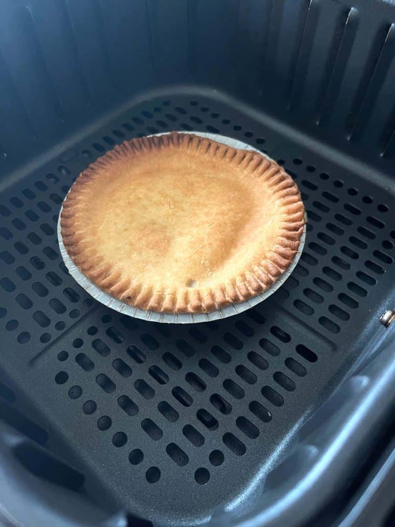 Golden brown turkey pot pie cooked in an air fryer basket, showing crisp crust achieved.