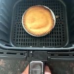 Frozen turkey pot pie cooking in an air fryer basket, showing how to cook pot pie directly from frozen for a crispy crust.