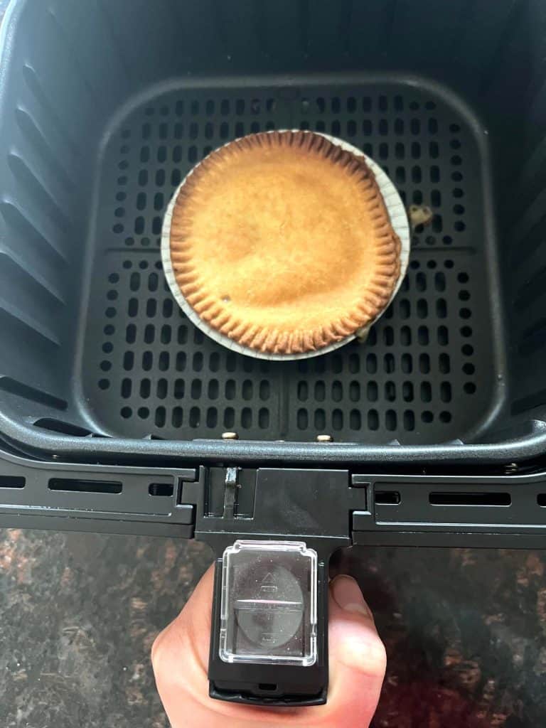 Frozen turkey pot pie cooking in an air fryer basket, showing how to cook pot pie directly from frozen for a crispy crust.