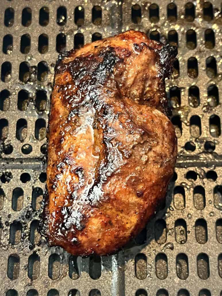 Close-up of a perfectly cooked duck breast with crispy, golden-brown skin inside the air fryer basket.
