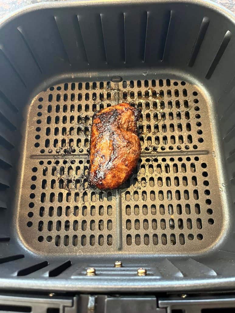 Golden brown duck breast in the air fryer basket after cooking, showing the crispy skin result.