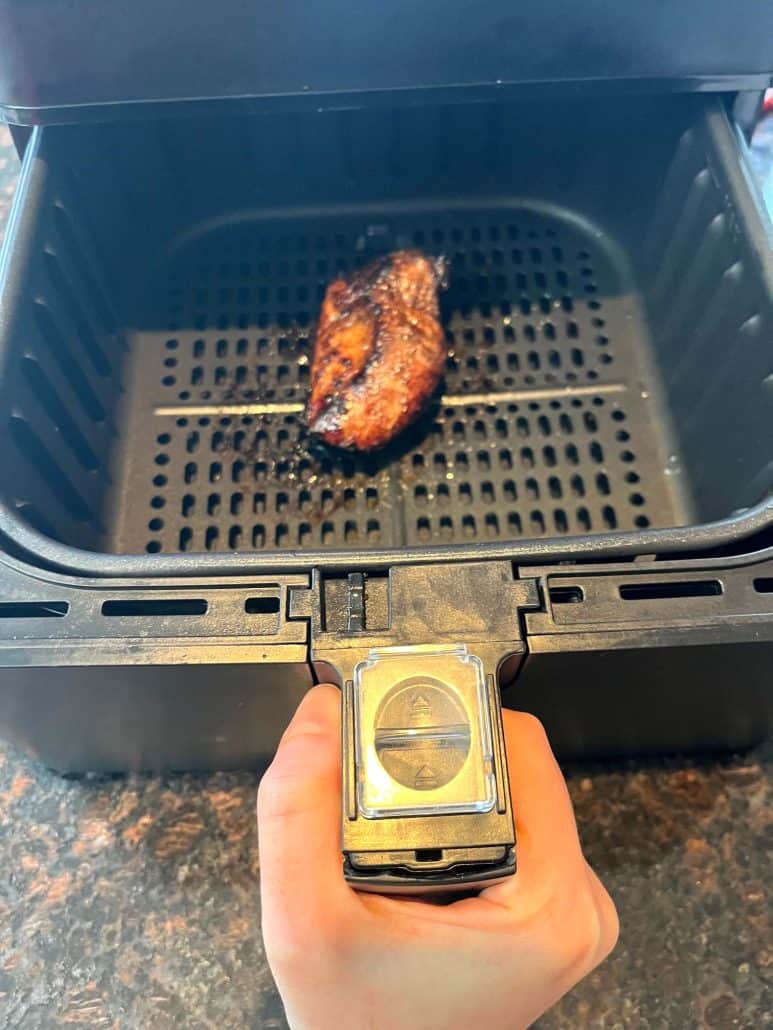 Cooked duck breast in an air fryer basket showing crisped skin after air frying.