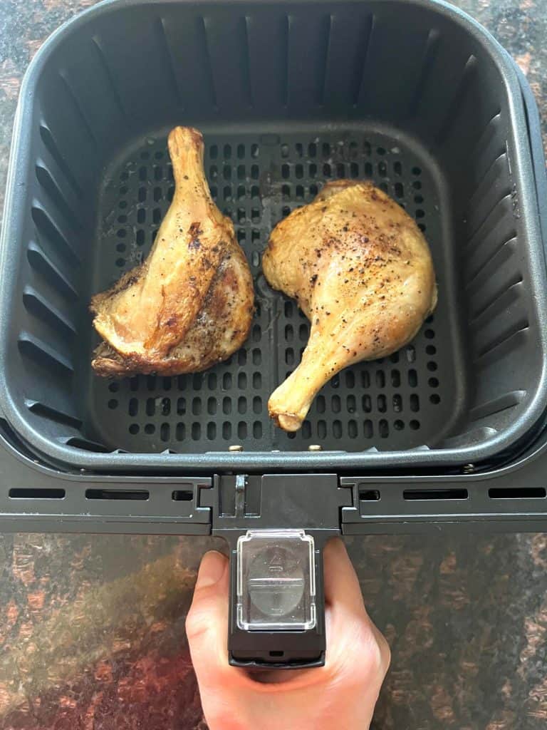 Cooked duck legs in an air fryer basket—crispy and golden brown, just like in the Air Fryer Duck Legs recipe.
