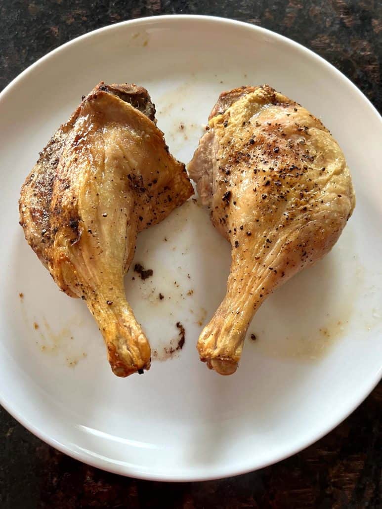 Two crispy air fryer duck legs served on a white plate, ready to enjoy.