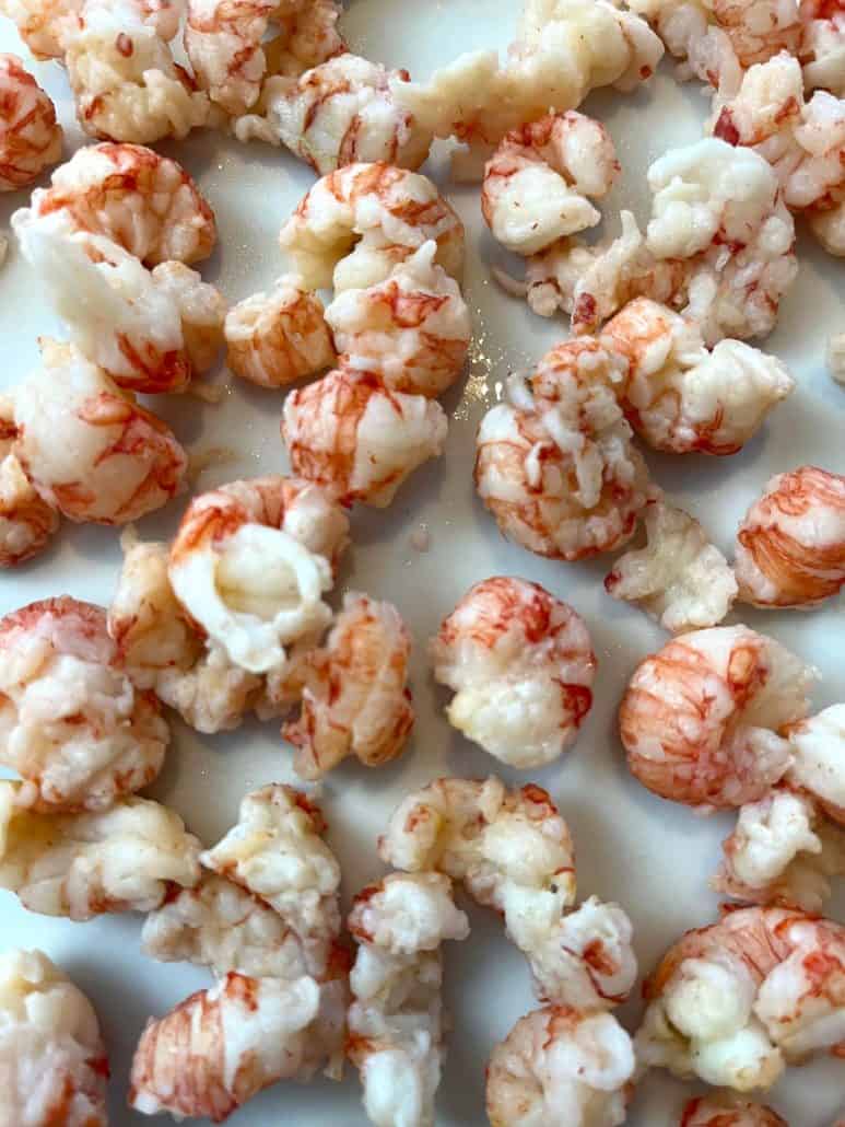 Close-up of perfectly cooked frozen langostino tails on a plate, showing their delicate texture.