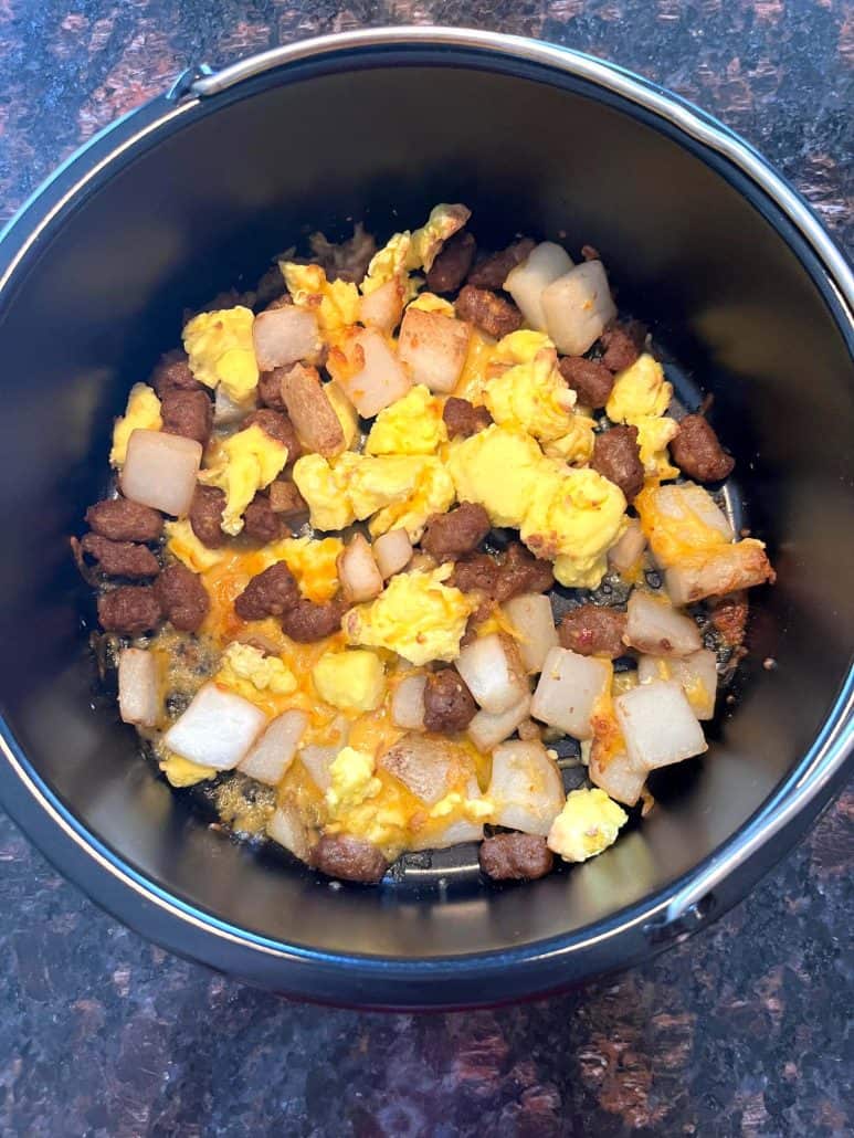 Cooked Jimmy Dean breakfast bowl in an oven-safe pan on the counter—featuring melted cheese, scrambled eggs, sausage, and potatoes after air frying.