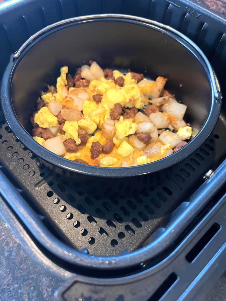 Fully cooked Jimmy Dean breakfast bowl in an oven-safe dish inside the air fryer basket—cheese melted perfectly on top.