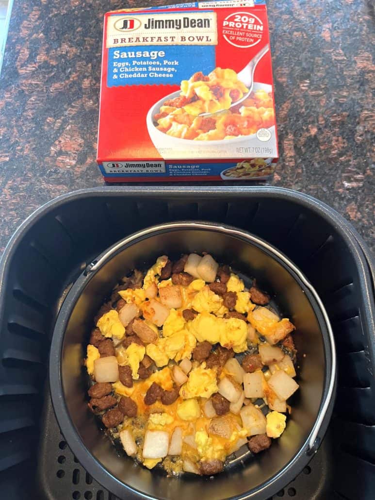 Cooked Jimmy Dean Breakfast Bowl inside an air fryer basket with the product box placed above it on the counter.
