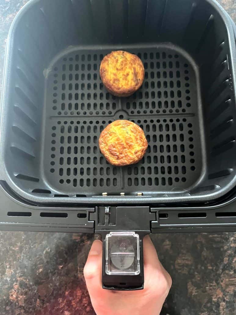 Two Jimmy Dean frittatas cooking in an air fryer basket, showing how to easily heat them from frozen for a quick breakfast.