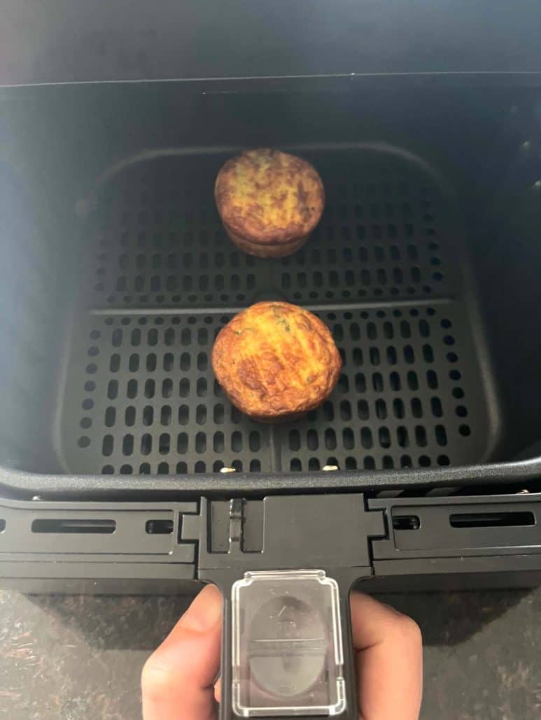 Two fully cooked, golden brown Jimmy Dean frittatas in an air fryer basket.