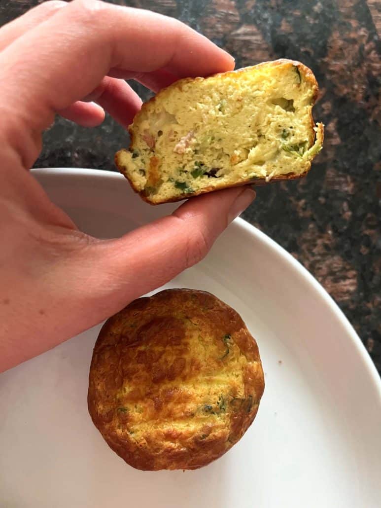 Melanie Mendelson from melaniecooks.com holding a sliced Jimmy Dean frittata to show the fully cooked inside, with another frittata on a plate.