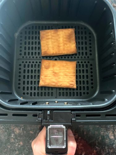 Two Pillsbury toaster pastries cooked in an air fryer basket, showing how they look perfectly browned and ready to frost.