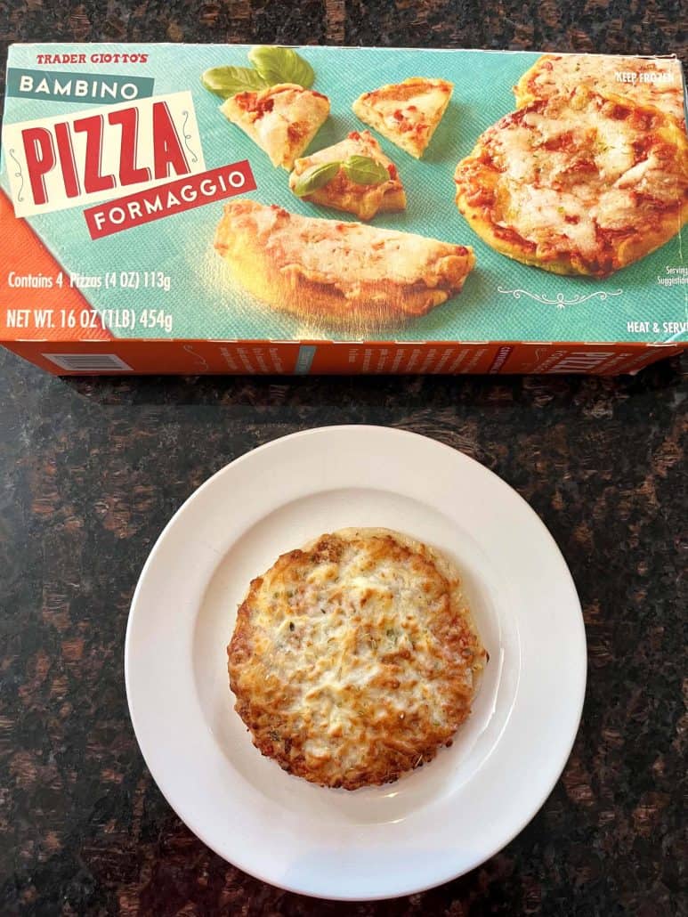 Cooked Trader Joe’s Bambino Pizza served on a white plate with the pizza box in the background, showing the finished air fryer mini pizza ready to eat.