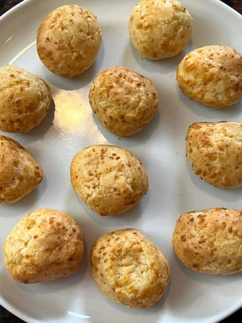 Golden brown Brazilian cheese bread on a white plate, showing the crispy texture from this quick and easy air fryer recipe.