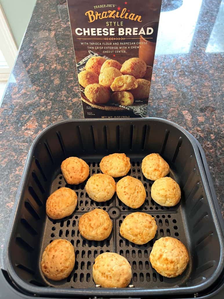 Cooked Trader Joe’s Brazilian Cheese Bread in an air fryer basket with the product box in the background, showing the final result of this easy air fryer recipe.