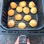 Air fryer basket filled with golden brown Brazilian cheese bread, cooked perfectly crispy on the outside.