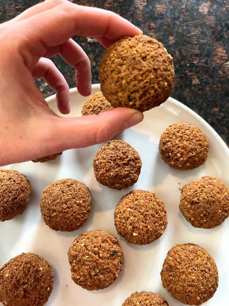 Melanie Mendelson from melaniecooks.com, holding a crispy air-fried Trader Joe’s Frozen Falafel over a plate. Showing the perfect golden texture from this easy air fryer recipe.