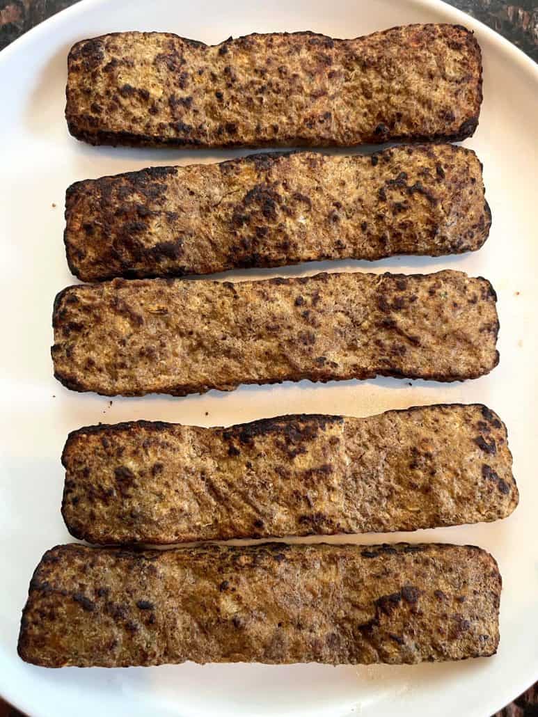 Five cooked Trader Joe’s beef kabobs neatly arranged on a plate, showcasing their crispy, browned exterior after air frying.