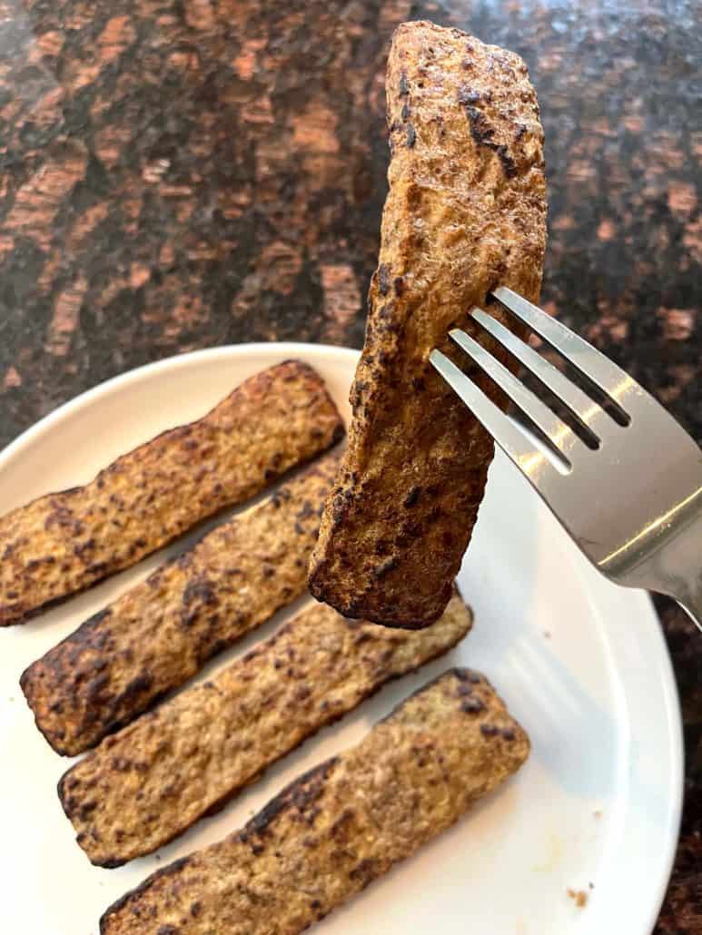 A fork lifting a cooked Trader Joe’s beef kabob from the plate, highlighting its crispy, golden-brown exterior.
