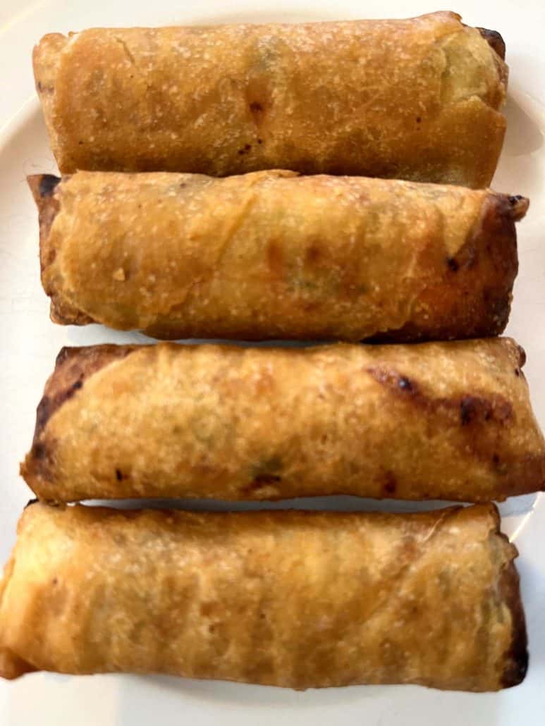 Close-up of four perfectly crispy and golden brown Trader Joe’s Chicken Spring Rolls on a plate.