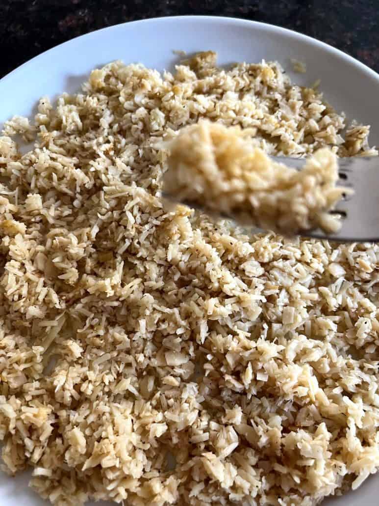 Hearts of palm rice on a fork above a plate – a healthy, keto-friendly rice substitute that’s light and satisfying.