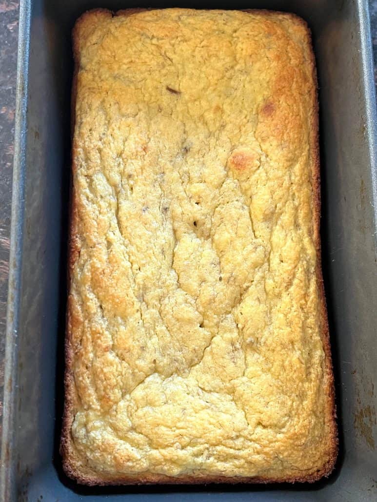 Freshly baked almond flour banana bread with golden top cooling in a loaf pan.