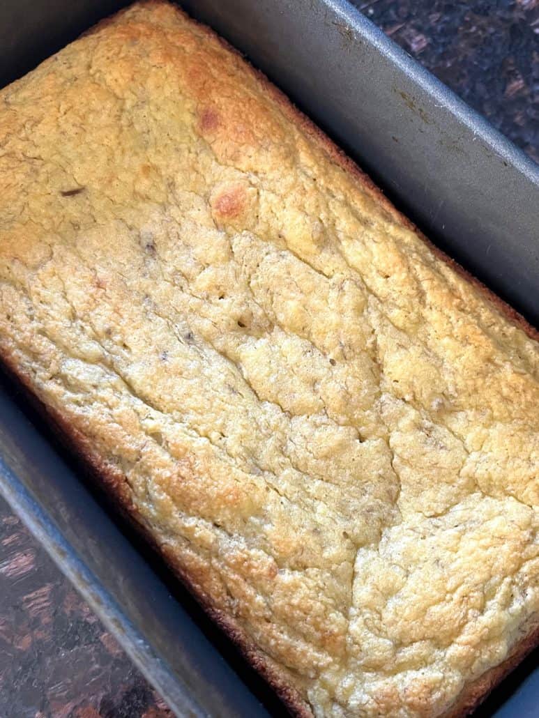 Golden almond flour banana bread cooling in loaf pan after baking.