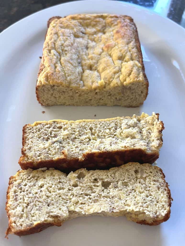 Sliced almond flour banana bread on a white plate, showing moist texture and golden crust.