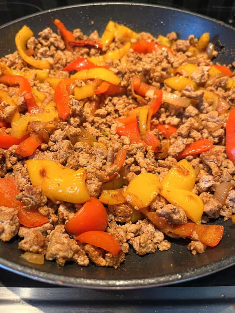 Ground turkey fajitas cooking in a skillet with colorful bell peppers and onions, showing the one-pan stovetop method from the recipe.