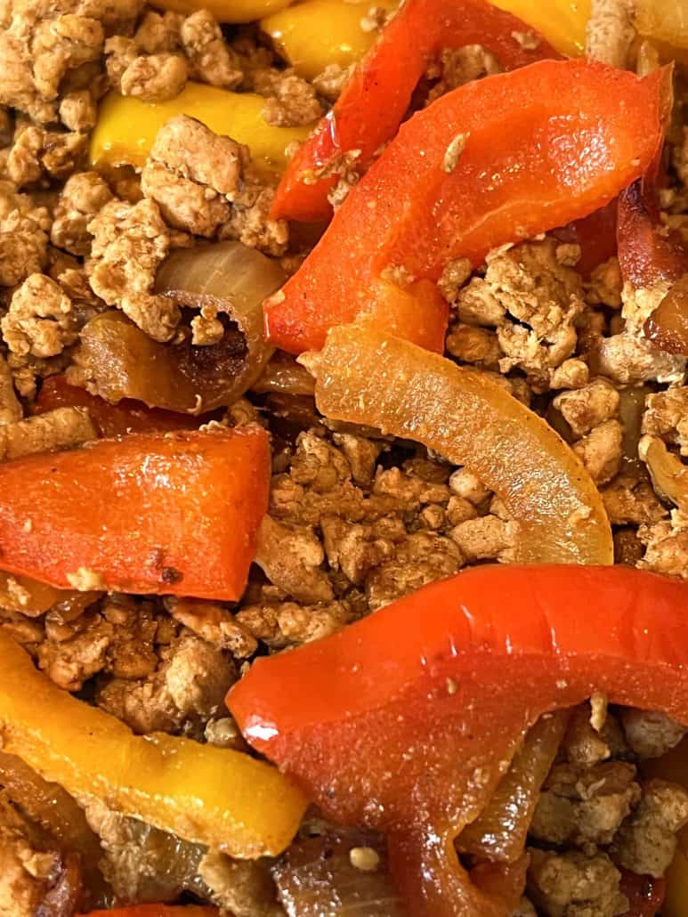 Close-up of cooked ground turkey fajitas showing seasoned meat, red and yellow bell peppers, and sautéed onions.