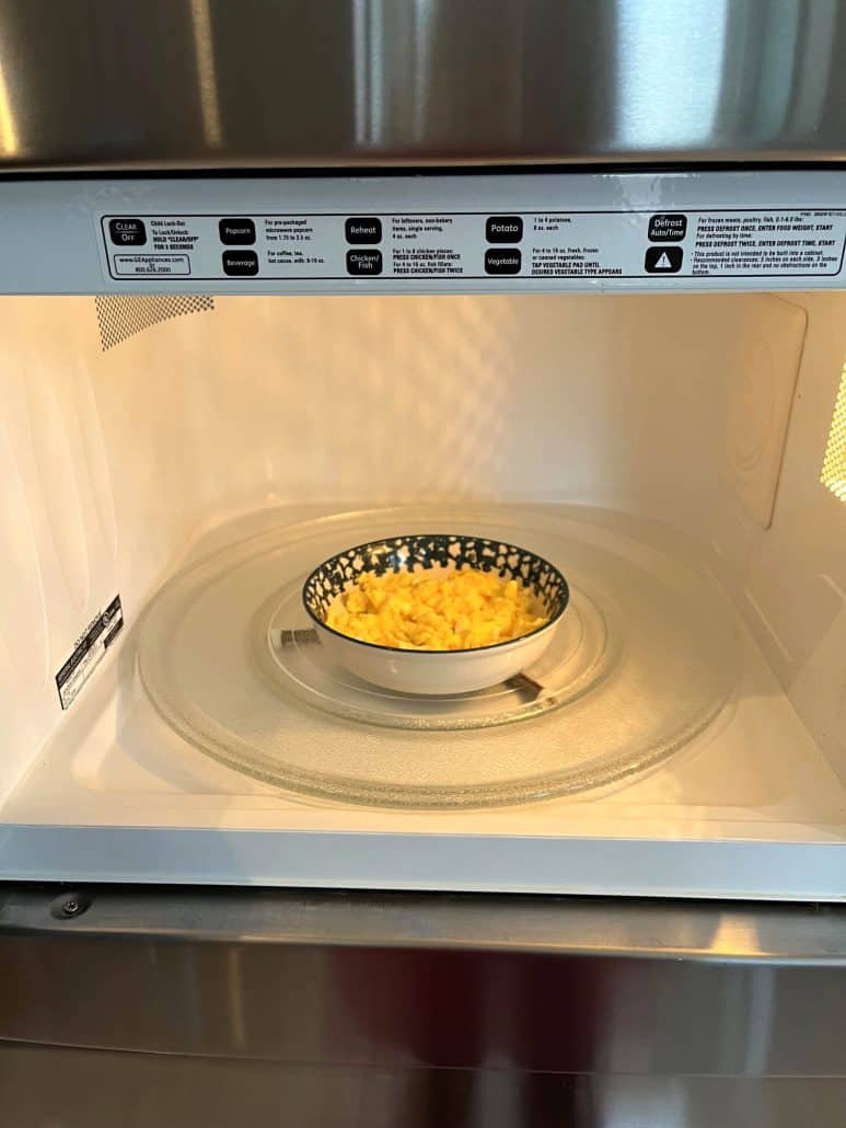 Bowl of scrambled eggs cooking in the microwave, showing the easy method for making eggs without a stove.