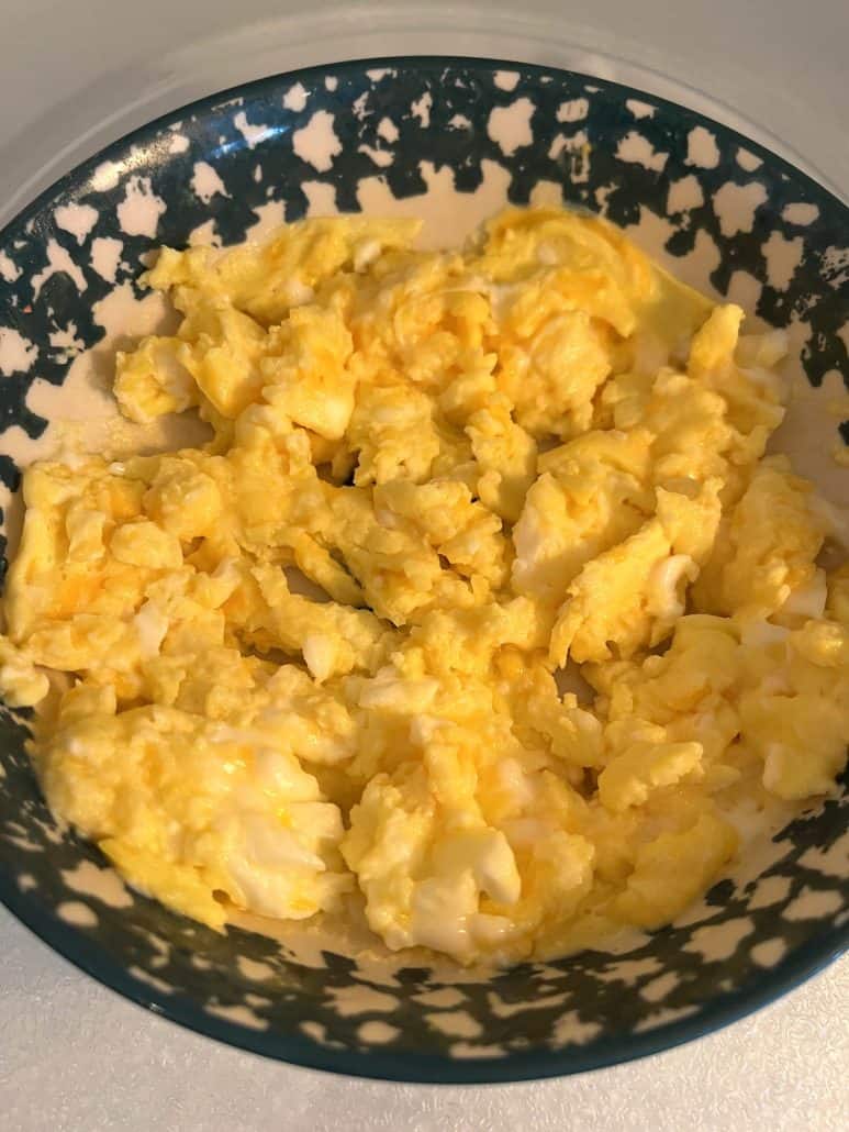 Microwave scrambled eggs in a bowl, showing their fluffy texture and golden color.