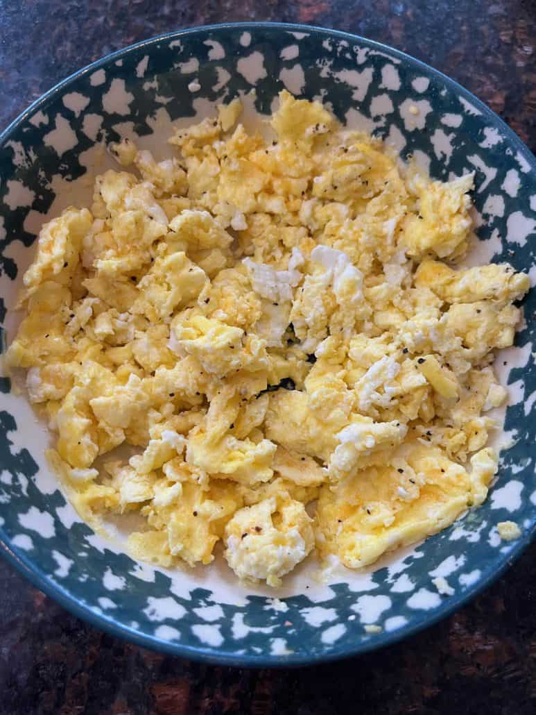 Fluffy scrambled eggs served in a patterned bowl, freshly made using the microwave method for a quick breakfast.