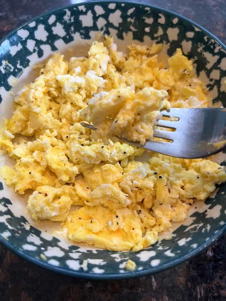 Microwave scrambled eggs in a bowl with a fork, ready to eat for a quick and easy breakfast.