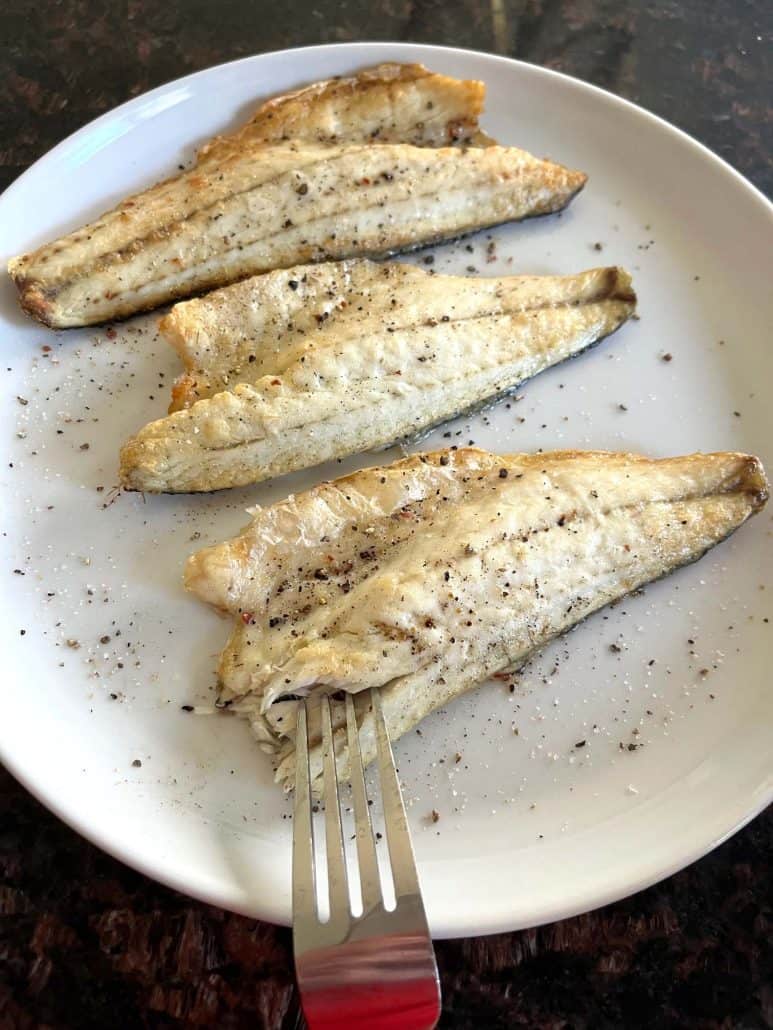 Cooked branzino fillets on a plate, seasoned with salt and pepper, as shown in the finished Air Fryer Branzino Fillets recipe.