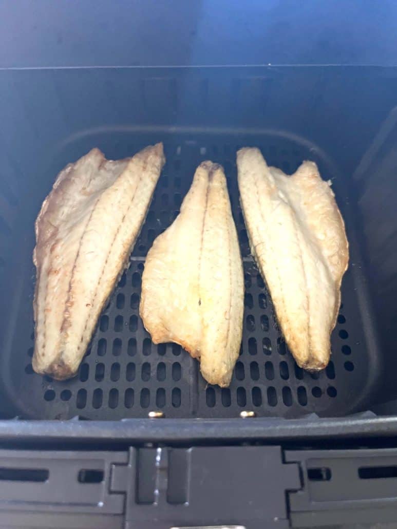 Air fryer basket with three cooked branzino fillets, shown as part of the Air Fryer Branzino Fillets recipe tutorial.